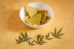solid weed butter in a bowl with cannabis leaf