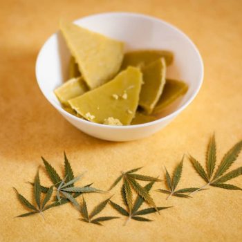 solid weed butter in a bowl with cannabis leaf